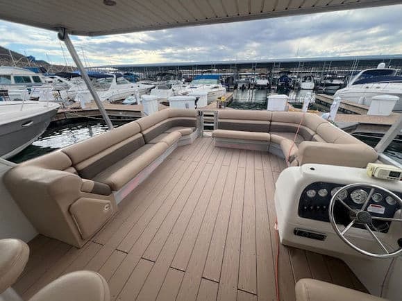 Spacious party boat deck with seating and steering wheel